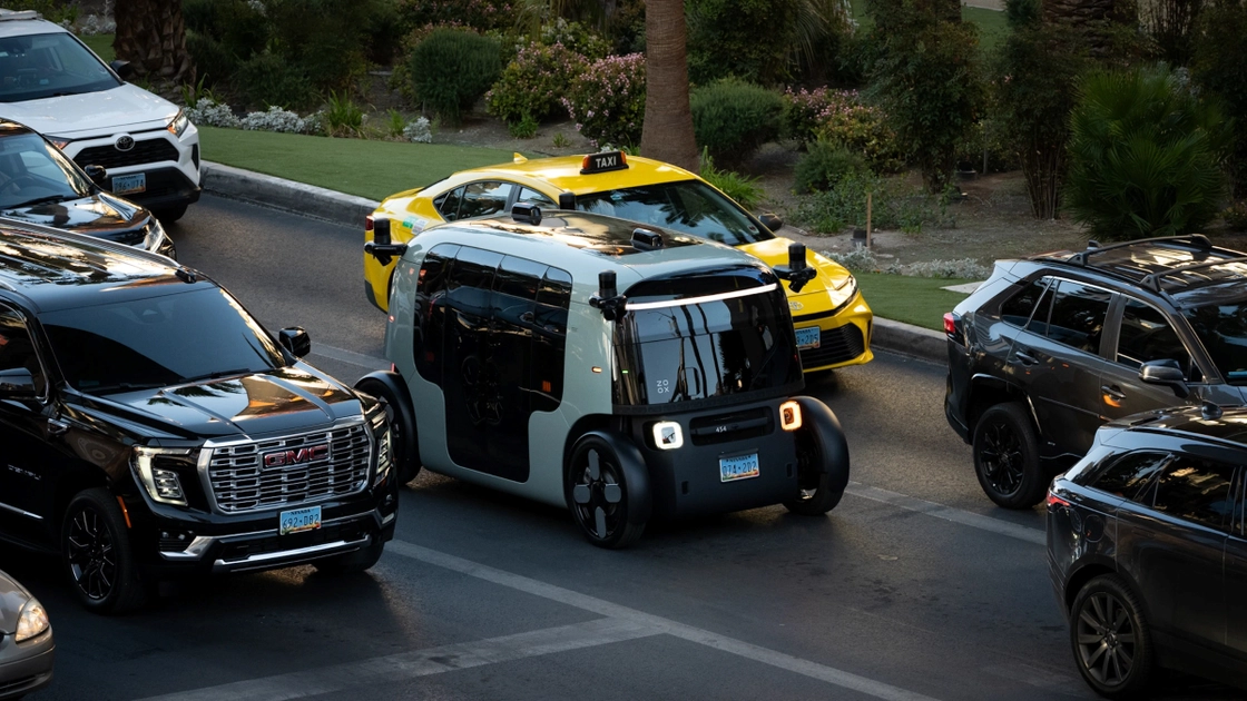 El robotaxi de Zoox en una calle urbana. Sin volante ni pedales, el habitáculo aloja a cuatro pasajeros cara a cara.
